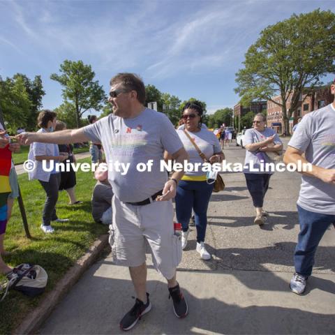 Corrie Svehla hands out a Husker Pride sticker during the Star City Pride parade on June 19. Other members of the campus group shown (left from Svehla) are Nkenge Friday, Pat Tetreault and Bill Nunez. More than 20 members of the university community marched together during Lincoln's first Star City Pride parade. A number of campus administrators, including Chancellor Ronnie Green and his wife, Jane, participated in the walk around the Nebraska State Capitol. Star City Pride parade on June 19, 2021. Photo by Troy Fedderson / University Communication.